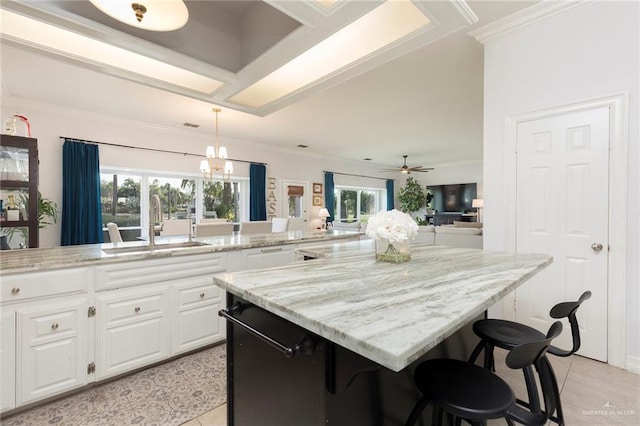 kitchen featuring a wealth of natural light, white cabinetry, a breakfast bar, and ceiling fan with notable chandelier