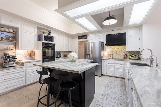 kitchen with white cabinets, sink, decorative light fixtures, and black appliances