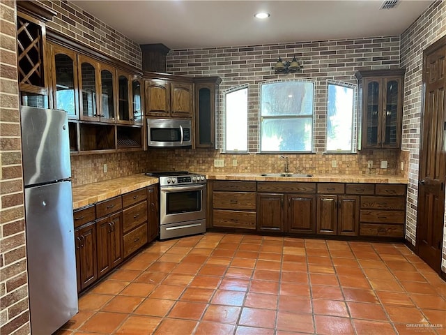 kitchen featuring tile patterned flooring, appliances with stainless steel finishes, dark brown cabinetry, and sink