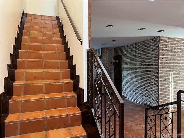 staircase with tile patterned flooring and brick wall