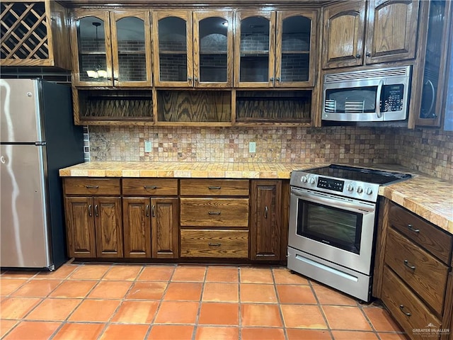 kitchen featuring dark brown cabinetry, decorative backsplash, and stainless steel appliances