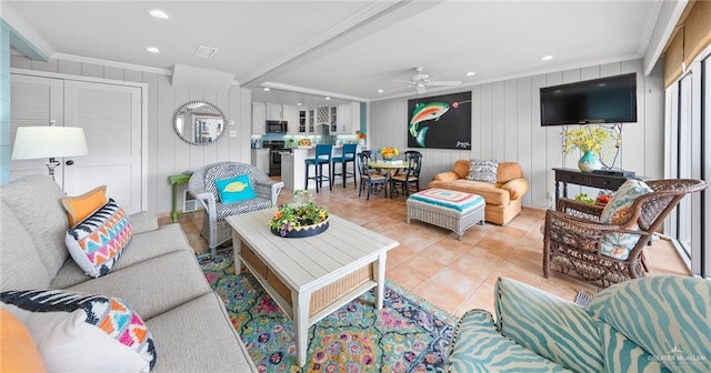 living room featuring wood walls, ceiling fan, crown molding, and light tile patterned flooring