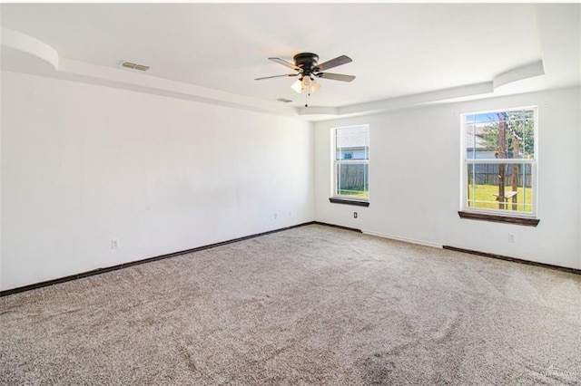 unfurnished room with ceiling fan, a raised ceiling, and carpet flooring