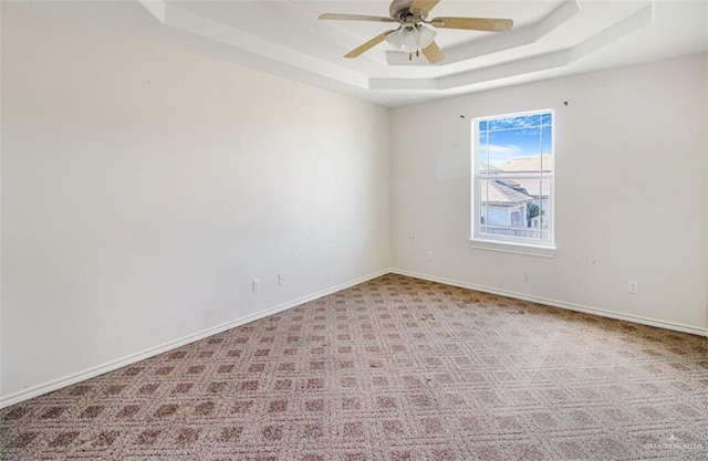 carpeted spare room featuring a raised ceiling and ceiling fan