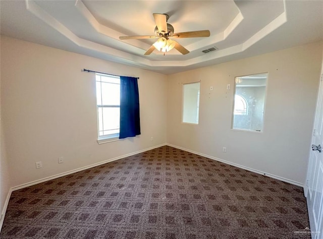 carpeted spare room with ceiling fan and a tray ceiling