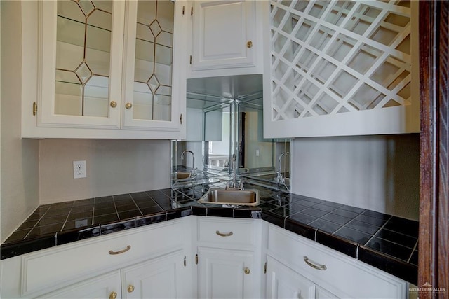 kitchen featuring white cabinets, tile countertops, and sink