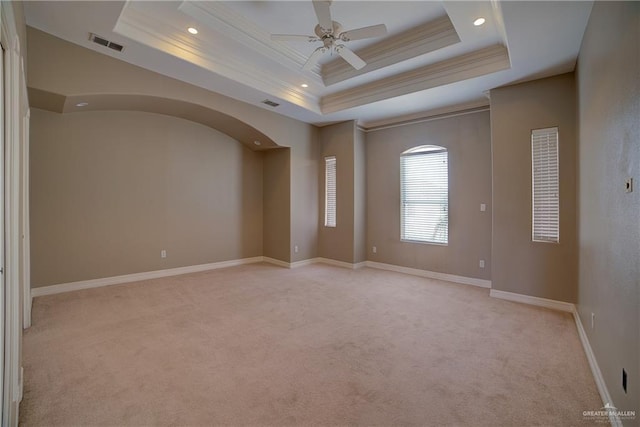 unfurnished room featuring ceiling fan, a raised ceiling, light colored carpet, and crown molding