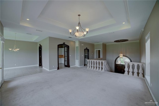 carpeted empty room featuring a chandelier, a raised ceiling, and ornamental molding