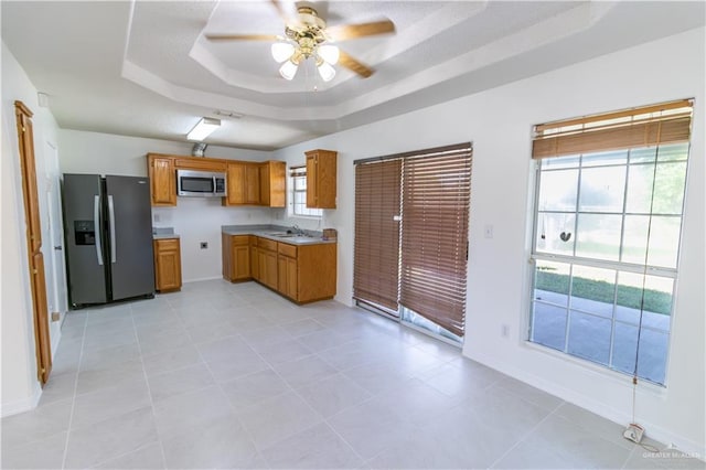 kitchen featuring a raised ceiling, sink, ceiling fan, light tile patterned floors, and appliances with stainless steel finishes