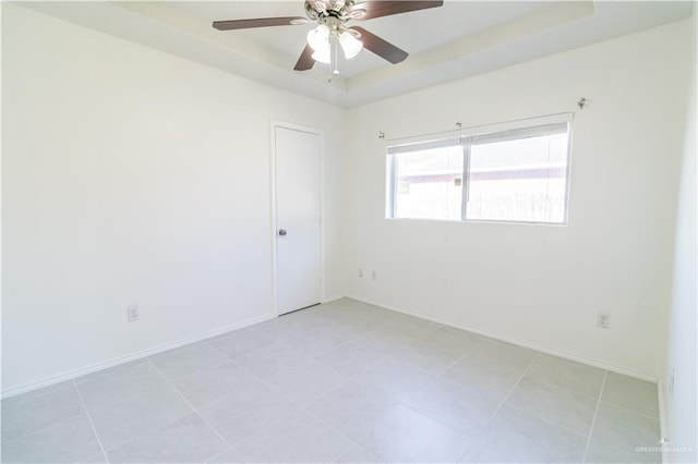 tiled empty room with a tray ceiling and ceiling fan