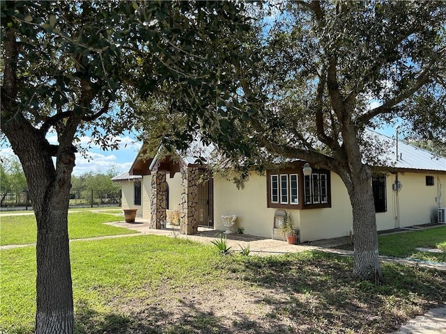 view of front of house featuring metal roof, a front lawn, and stucco siding