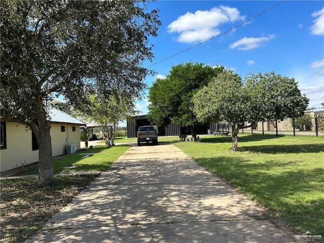 exterior space featuring metal roof, central AC unit, driveway, a carport, and a front yard