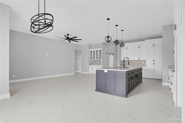 1915 Chandler Cir, Edinburg, TX 78542 - kitchen with backsplash, light marble finish flooring, ceiling fan, white cabinets, and a kitchen island with sink