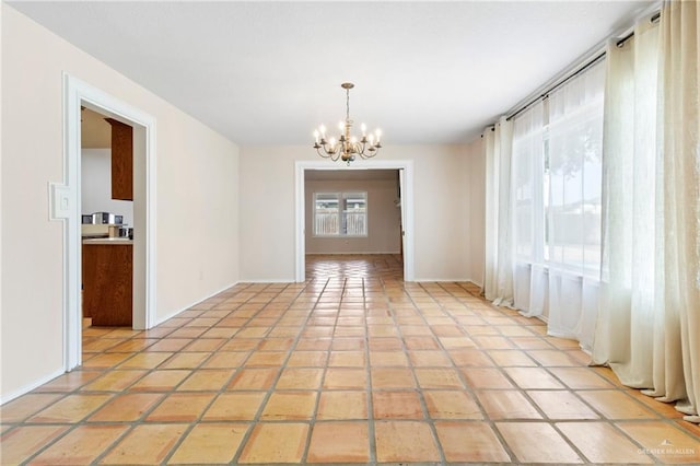 spare room with baseboards, a notable chandelier, and light tile patterned flooring