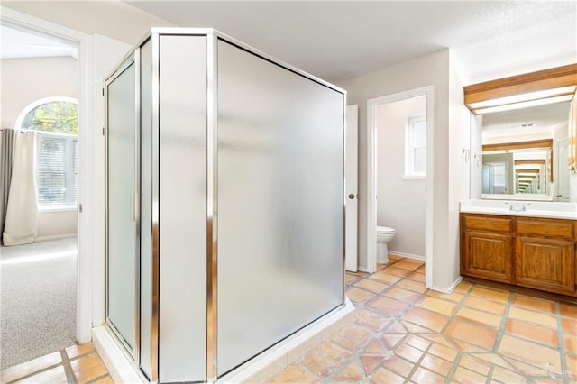 full bath featuring toilet, a stall shower, baseboards, and vanity