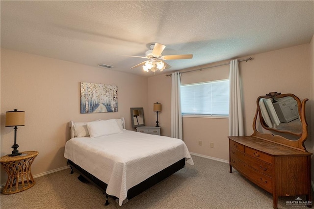 bedroom with a textured ceiling, light colored carpet, and ceiling fan