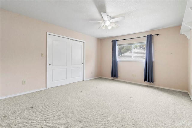 unfurnished bedroom featuring a closet, a ceiling fan, carpet flooring, a textured ceiling, and baseboards