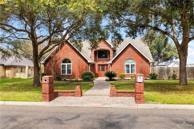 traditional-style home with fence, a front lawn, and brick siding