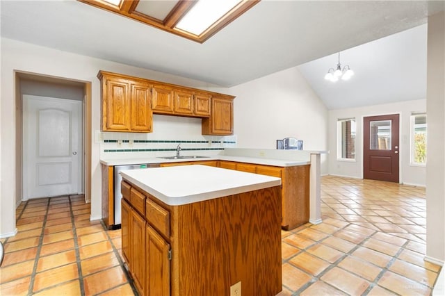 kitchen featuring a center island, light countertops, vaulted ceiling, a sink, and dishwashing machine