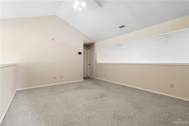 carpeted spare room with visible vents, vaulted ceiling, and baseboards