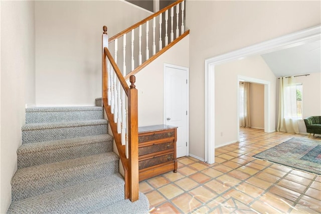 staircase featuring a high ceiling and tile patterned floors