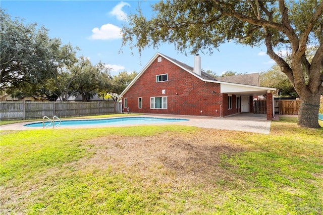 back of house featuring brick siding, fence, a yard, a fenced in pool, and a patio area