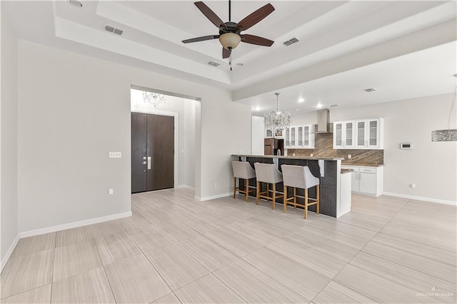 4630 Kristine Dr, Harlingen, TX 78552 - kitchen with refrigerator, wall chimney range hood, visible vents, a breakfast bar, and a raised ceiling