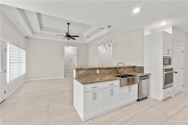 4630 Kristine Dr, Harlingen, TX 78552 - kitchen featuring dark stone countertops, a peninsula, appliances with stainless steel finishes, ceiling fan with notable chandelier, and a sink