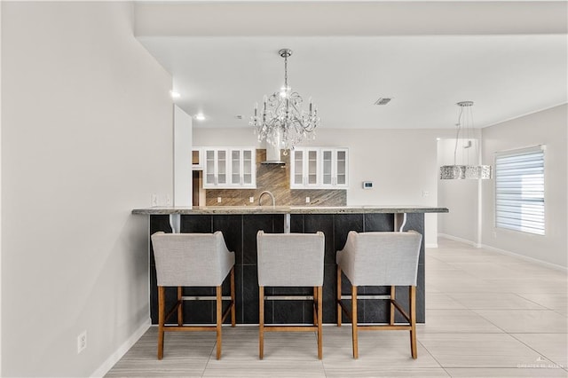 4630 Kristine Dr, Harlingen, TX 78552 - kitchen featuring white cabinets, tasteful backsplash, baseboards, and a breakfast bar area