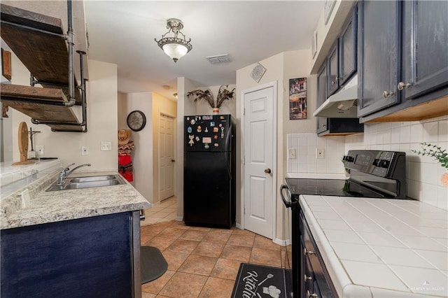 605 W Lozano St, Harlingen, TX 78550 - kitchen with black appliances, under cabinet range hood, tasteful backsplash, light tile patterned flooring, and tile countertops
