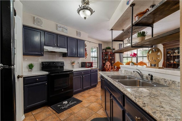 605 W Lozano St, Harlingen, TX 78550 - kitchen with under cabinet range hood, black appliances, open shelves, decorative backsplash, and light countertops