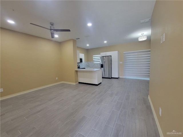 kitchen with appliances with stainless steel finishes, light wood-type flooring, backsplash, ceiling fan, and white cabinetry