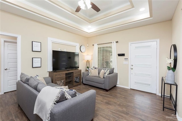 living room with ceiling fan, a tray ceiling, and dark hardwood / wood-style floors