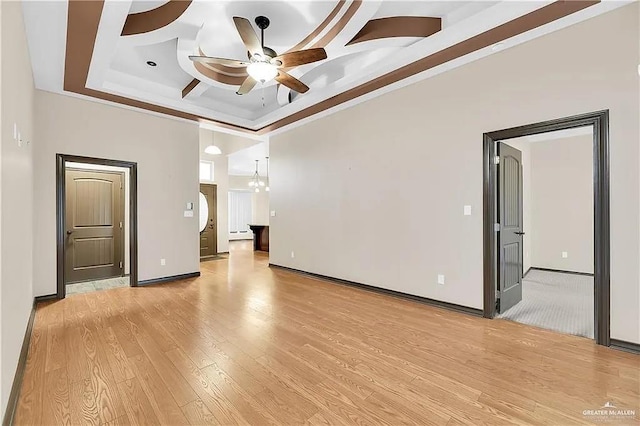 unfurnished room with crown molding, ceiling fan with notable chandelier, light hardwood / wood-style flooring, and a high ceiling