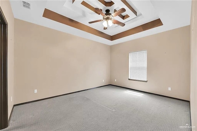 empty room with a raised ceiling, carpet floors, and ceiling fan