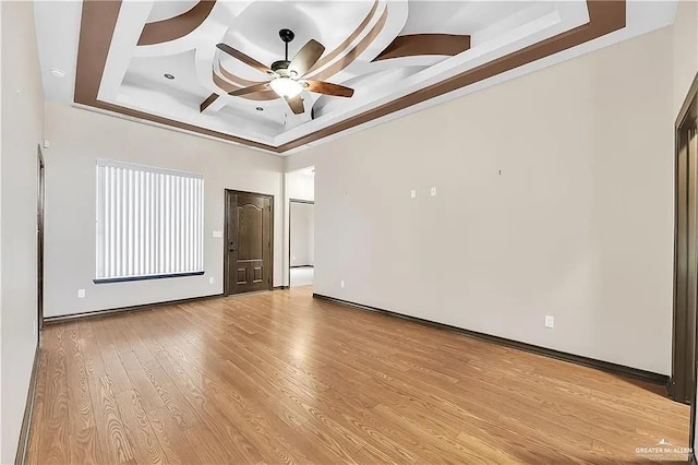 empty room with ceiling fan, coffered ceiling, light hardwood / wood-style floors, and a towering ceiling