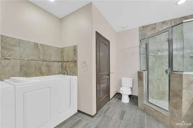 bathroom with toilet, independent washer and dryer, tile patterned floors, and plus walk in shower