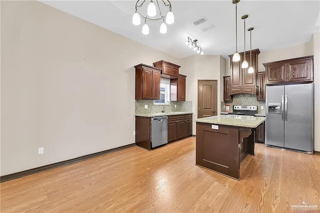 kitchen with decorative light fixtures, a center island, dark brown cabinets, light wood-type flooring, and appliances with stainless steel finishes