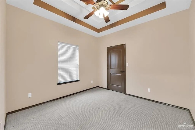 empty room with light colored carpet, a raised ceiling, and ceiling fan