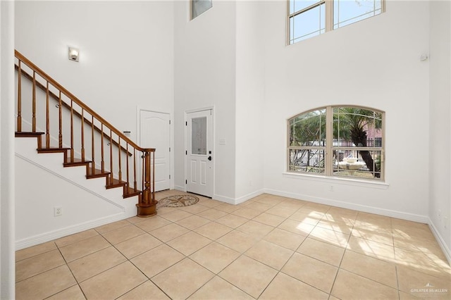 tiled entrance foyer with a high ceiling and a healthy amount of sunlight