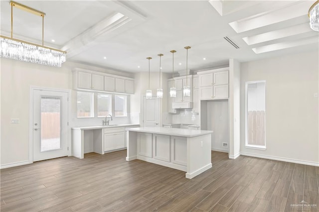 4312 Xenops Ave, Mcallen, TX 78503 - kitchen with white cabinetry, a kitchen island, wood finished floors, light countertops, and baseboards