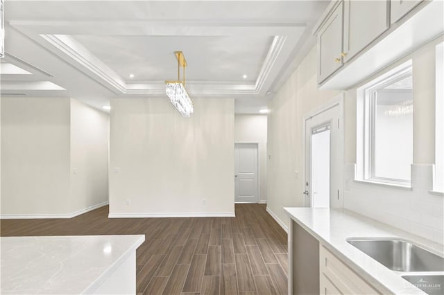 4312 Xenops Ave, Mcallen, TX 78503 - unfurnished dining area featuring a raised ceiling, dark wood-style flooring, baseboards, a sink, and crown molding