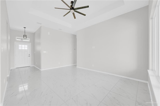 empty room with a raised ceiling and ceiling fan