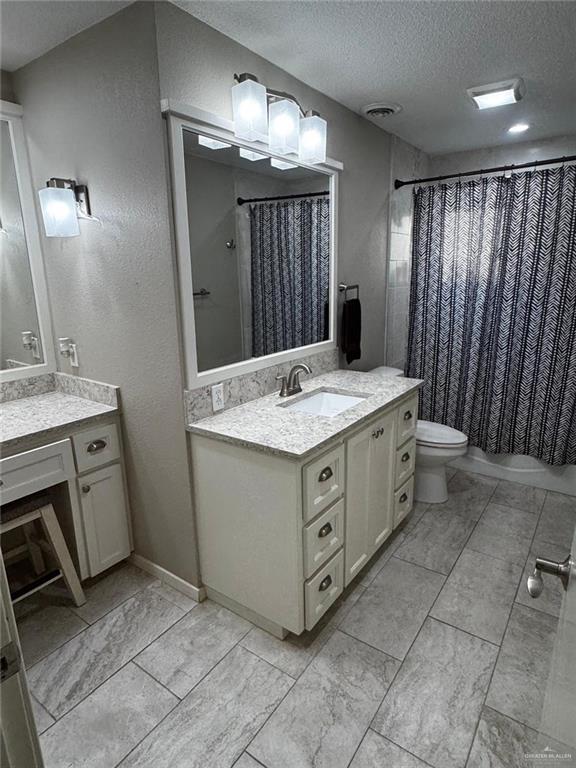 1108 Ash Dr, Weslaco, TX 78596 - full bath with a textured ceiling, vanity, toilet, and curtained shower