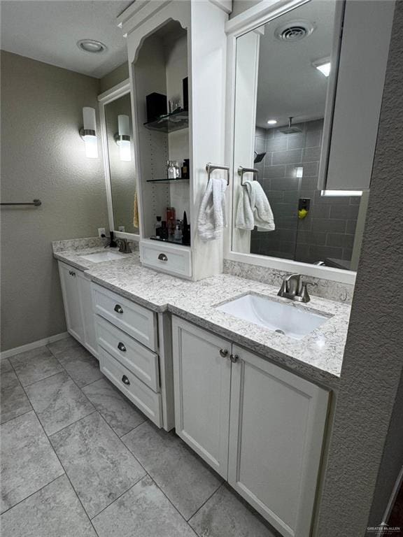 1108 Ash Dr, Weslaco, TX 78596 - full bathroom featuring double vanity, a textured wall, and a tile shower