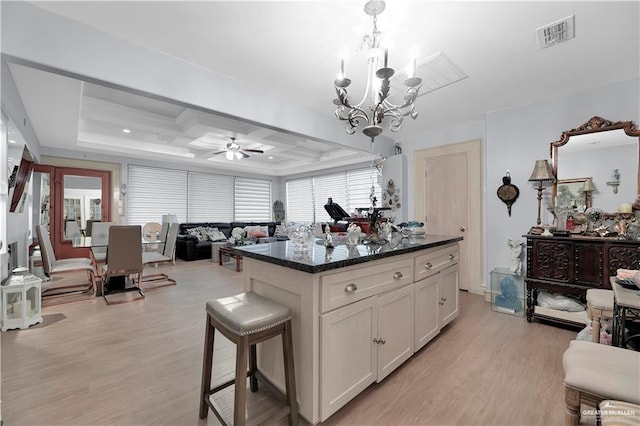 kitchen with white cabinetry, hanging light fixtures, dark stone countertops, a center island, and light hardwood / wood-style floors