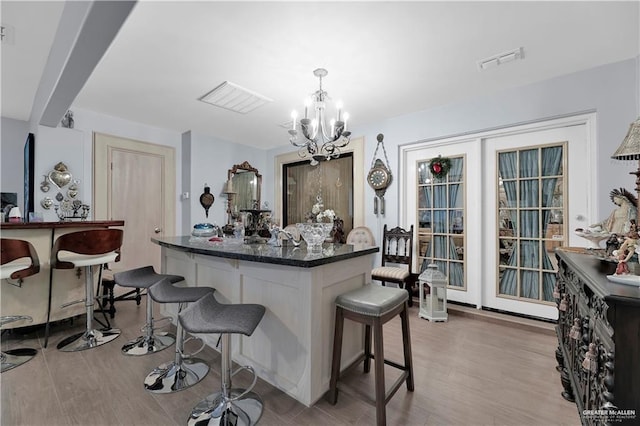 kitchen featuring an inviting chandelier, a breakfast bar, hanging light fixtures, and hardwood / wood-style flooring