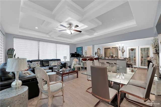 dining area with coffered ceiling, ceiling fan with notable chandelier, and light wood-type flooring