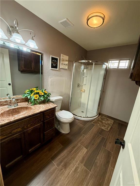 812 W Falcon Ave, Pharr, TX 78577 - bathroom featuring vanity, wood finished floors, a stall shower, and toilet