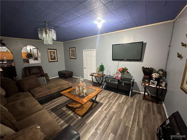 living room with hardwood / wood-style flooring, crown molding, and a chandelier